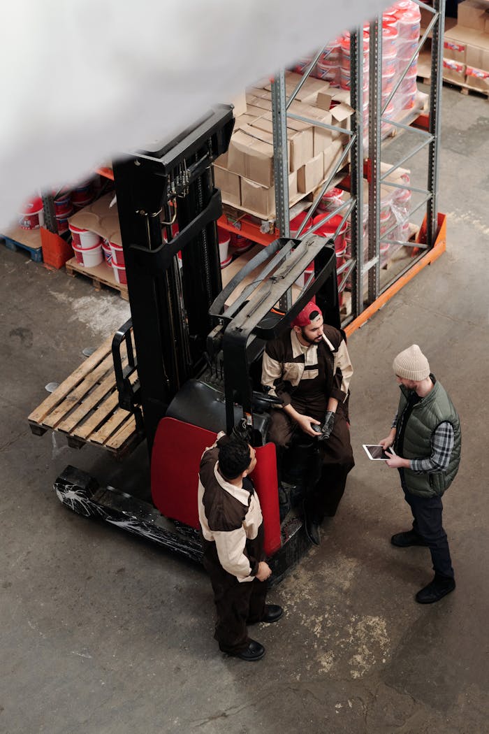 Overhead view of warehouse workers having a meeting with forklift equipment. Collaborative workplace scenario.